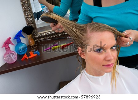 stylist working on woman hair in salon