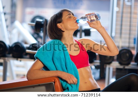 woman in gym drinks from water bottle