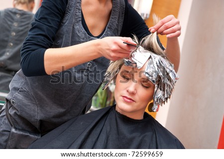woman coloring her hair in hairdresser salon