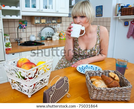 woman drinking coffee and eat breakfast at the table in kitchen