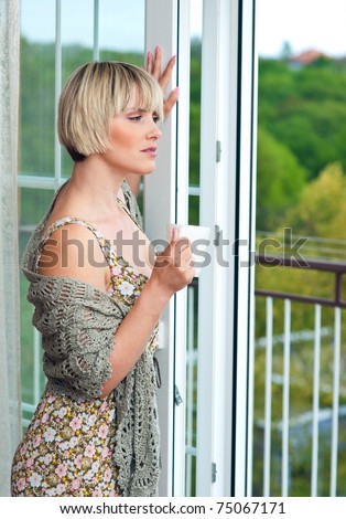 woman with morning coffee looking through window
