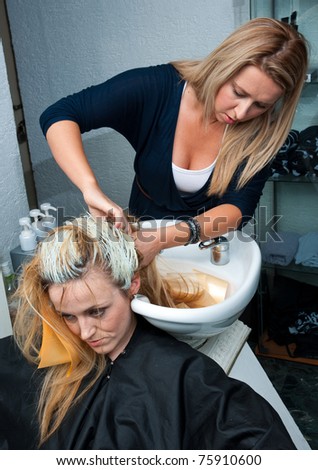 stylist removing coloring foils from woman hair