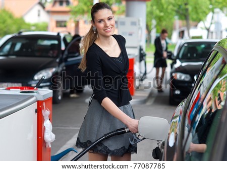 woman holding fuel nozzle and refuel car in gas station