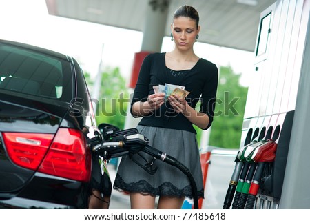 woman holding money when refuel car in gas station