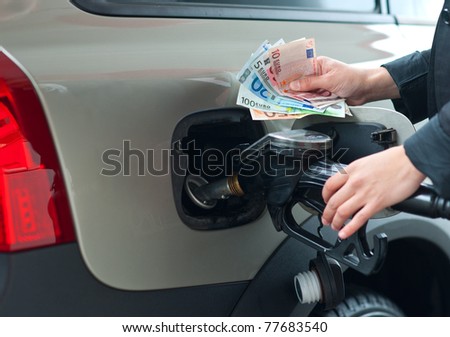 woman hand refuel car holding gas nozzle and money in gas station