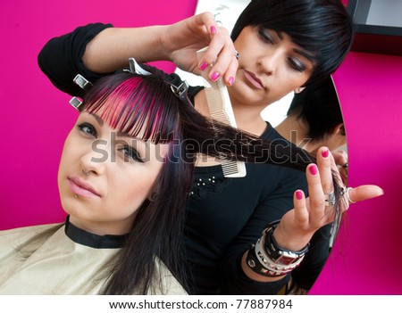 stylist making hair style to interesting looking teen girl