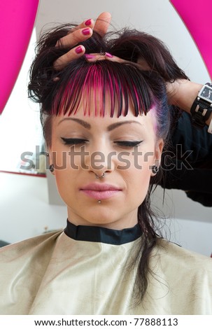 emo style looking teen girl with pink hair in sitting in salon chair