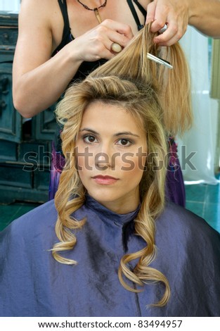 hair stylist curling woman hair in salon