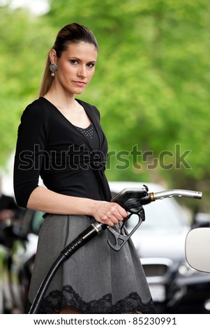 attractive woman holding nozzle at gas station