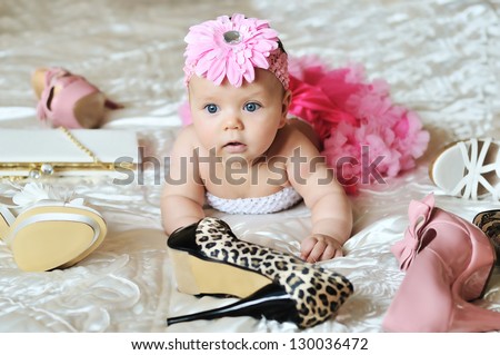 baby girl wearing tutu  laying on the bed with high heels shoes and bags