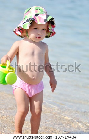 funny toddler girl on the beach in sea water