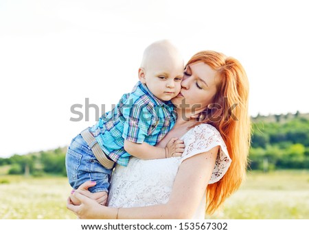 mother kissing baby son in field