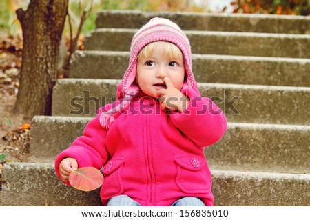 baby girl picking her nose outdoors