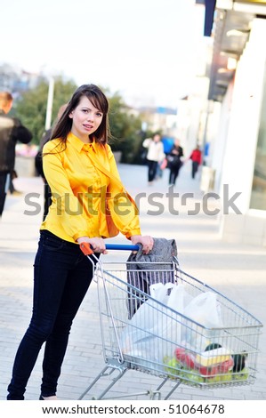 girl  with shopping trolley going from shop to car