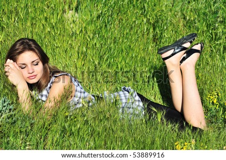young teen girl dreaming in the green grass