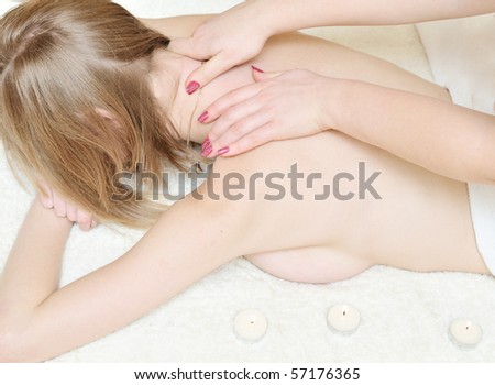 pretty young woman relaxing under hands of massage therapist during massage of neck
