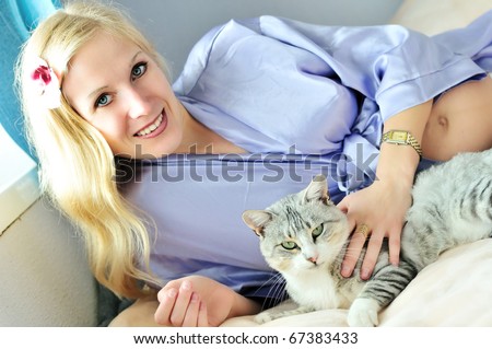 happy pregnant woman with cat laying on the sofa
