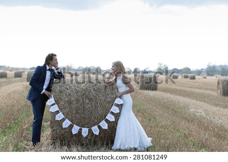 Married couple standing with the elbows on a hay bale that is written Just married.