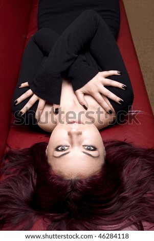 Fashion red haired girl looking at camera while hugging self. Focus on eyes.