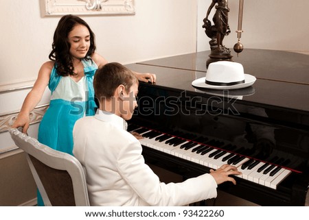 Lovely young lady admiring his boy performing at a grand piano. Please see more images from the same shoot.
