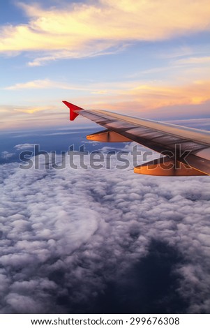 Colors through the plane\'s window.\
Aerial view from the plane. The beautiful sunset color paint the sky and the island are simply seen through the thin layers of clouds.