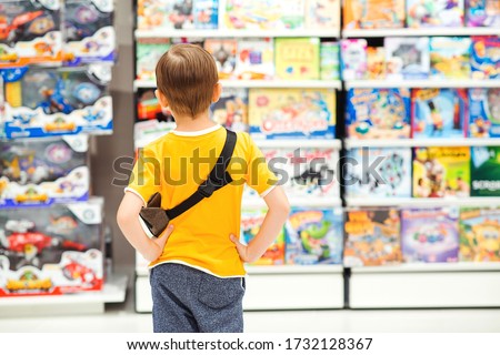 Little boy choosing toys for birthday gift. Many toys around. Kids shop. Sales, discounts and shopping. Cute boy selecting toys in store. Child doing shopping in toys shop.