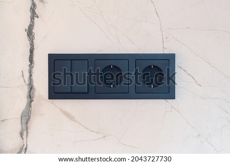 New black switch and socket on the marble wall. Kitchen background. Electric light switch and socket on the empty wall. Electrical power socket and plug switched. Сток-фото © 