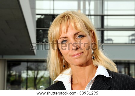 Business woman in front of office building - smiling.