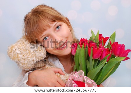 beautiful girl with teddy bear and bouquet of red tulips