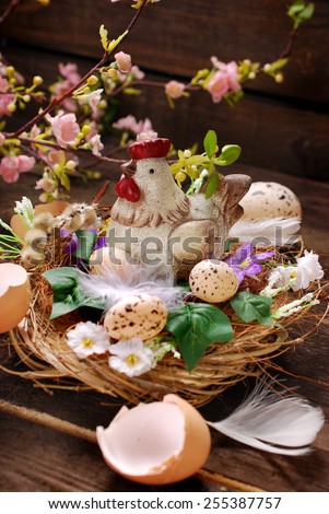 easter decoration with hen figurine in the nest and eggs on wooden background