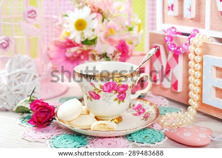 tea in fine china cup with roses ornament and anise meringue cookies in romantic style
