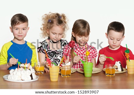 Four cheerful children celebrate a birthday at the table