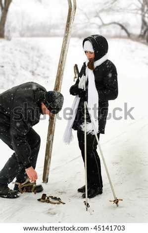 The father helps the twelve years daughter to learn to ski.
