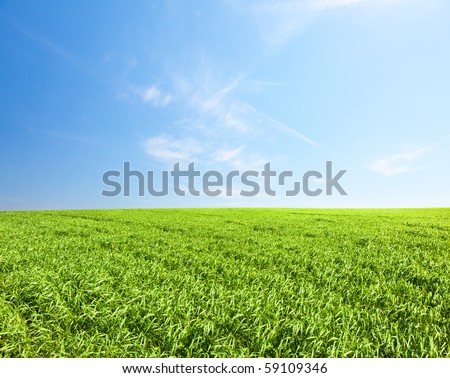 Green hill under blue cloudy sky whit sun