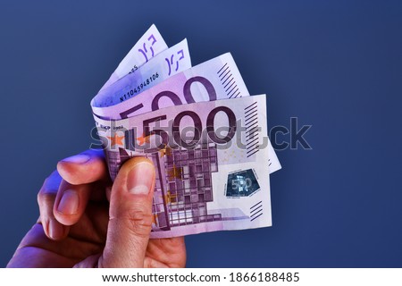 A rich man hand shows 1000 Euros in two 500 euro banknotes on a blue background. concept of earning, wealth, salary, pension 商業照片 © 