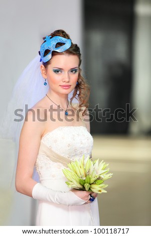 beautiful young bride wearing in white dress with blue makeup and mask in hairdo