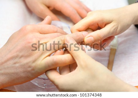 Female hands make manicure for man in beauty salon; hand care