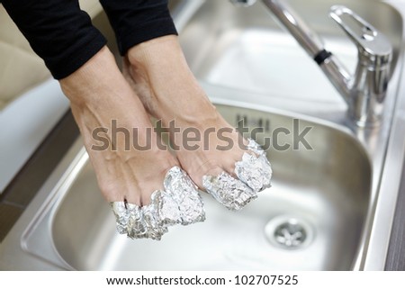 Female feet with fingers wrapped in cosmetic foil.