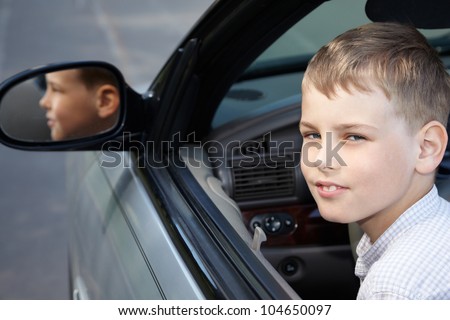 A boy sits half-turned back on a driver place in a open top car