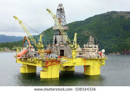 Ocean offshore oil rig drilling platform off near wooded shore of Stavanger, Norway.