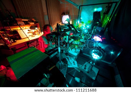 Scientist engaged in research in his lab about movement of microparticles by laser in dark lab