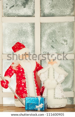 miniature toy Santa Claus, Snow Maiden near frost window