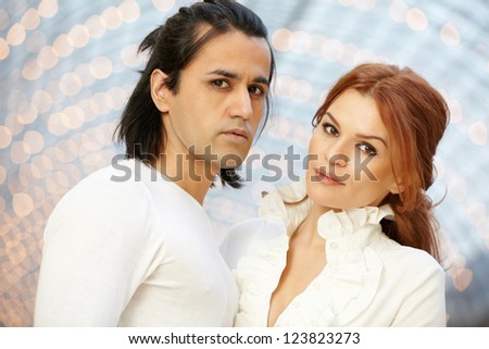 Dark-haired man and red-haired woman stand side by side and look ahead