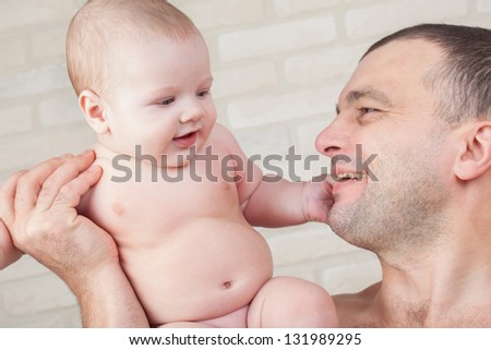 Happy baby and a strong father looking at each other