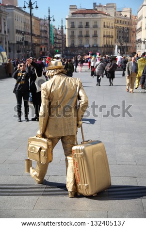MADRID - MARCH 9: Lively sculpture - golden man with big bag at street on March 9 2012 in Madrid, Spain. In 2012 number of tourists in resorts of Spain increased 1.5 times compared to 2011.