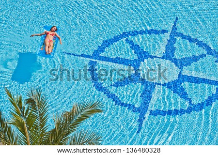 Woman has a rest on inflatable mattress in pool with wind rose image at bottom