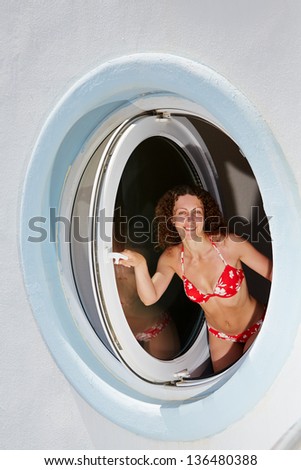 Young smiling woman look out from made in form of porthole