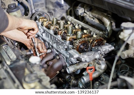 Mechanic hands tighten nut with wrench while repairing engine