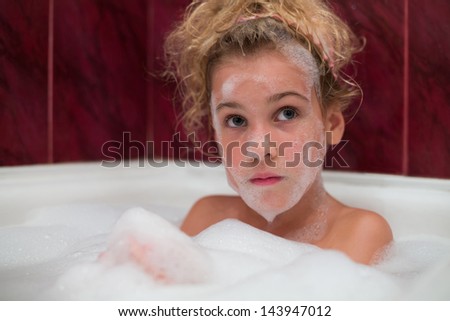 Little girl in a bath with foam on his face