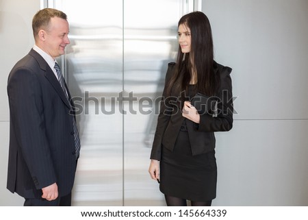 Man and woman in business suits waiting for elevator